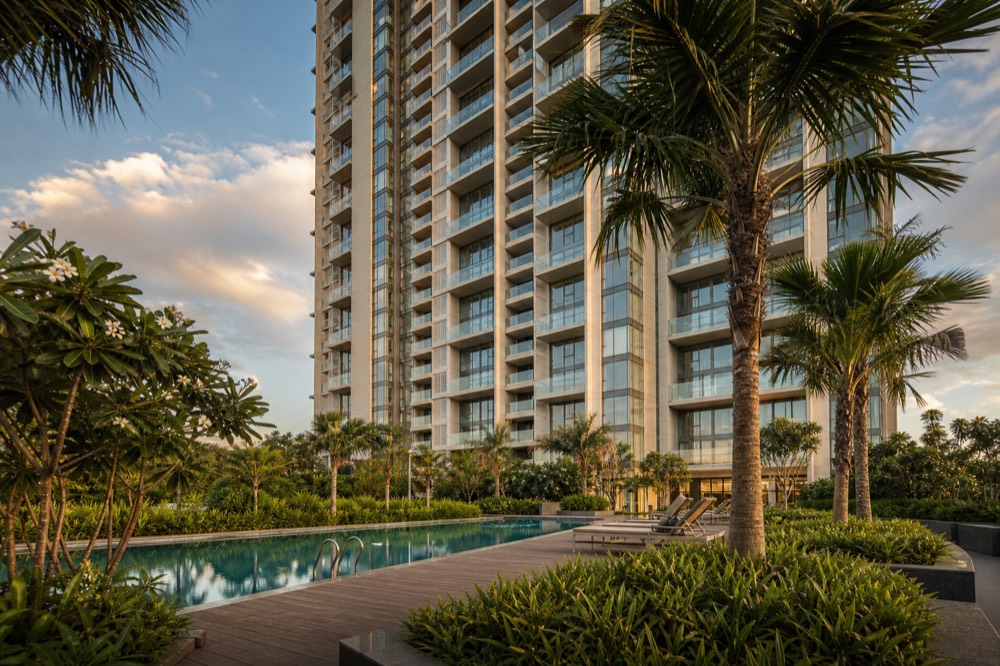 Apartment tower above a landscaped pool deck with palms
